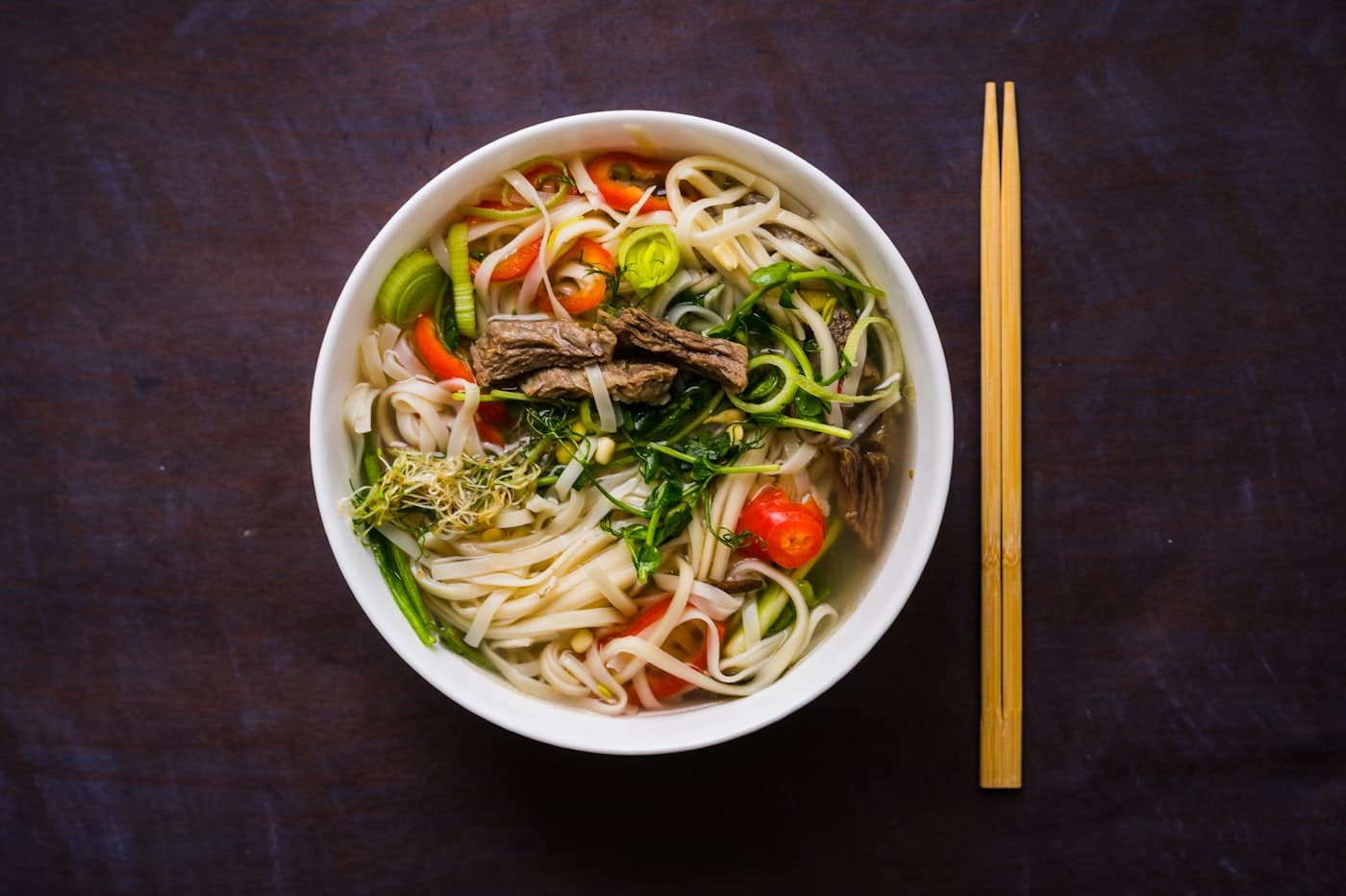 A bowl of noodle soup with chopsticks