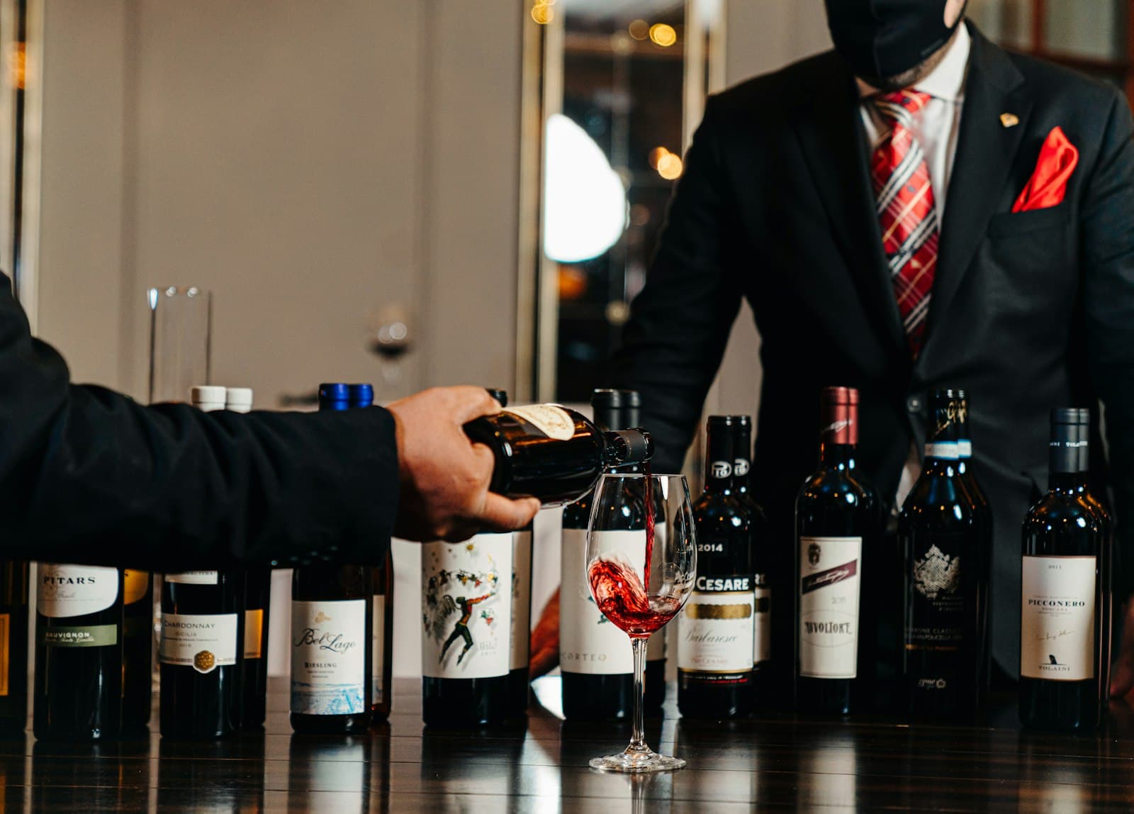 Wine being poured beside a row of bottles