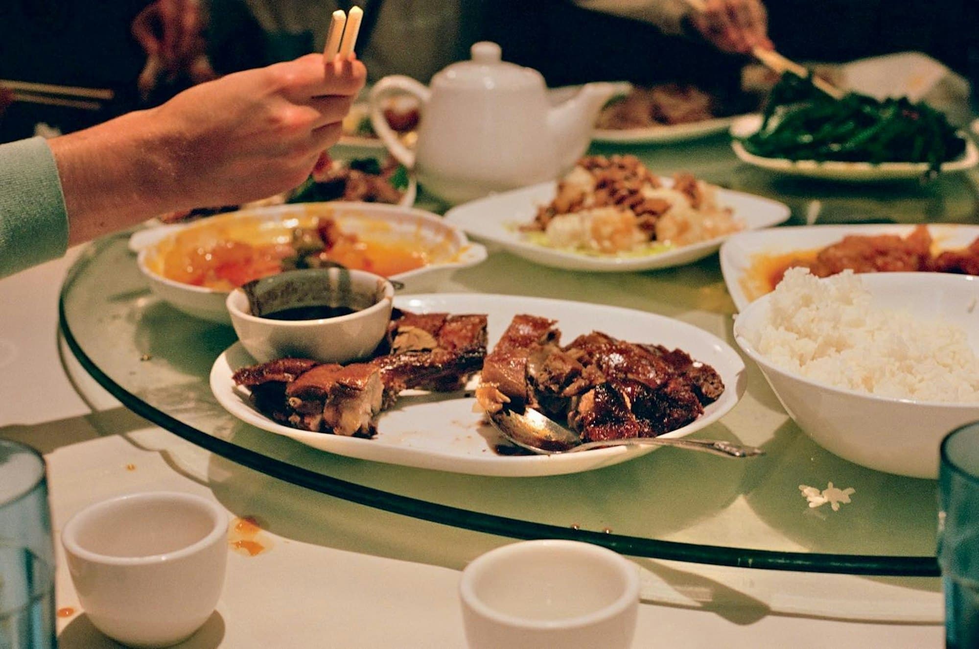 A family sharing a round table of Chinese dishes