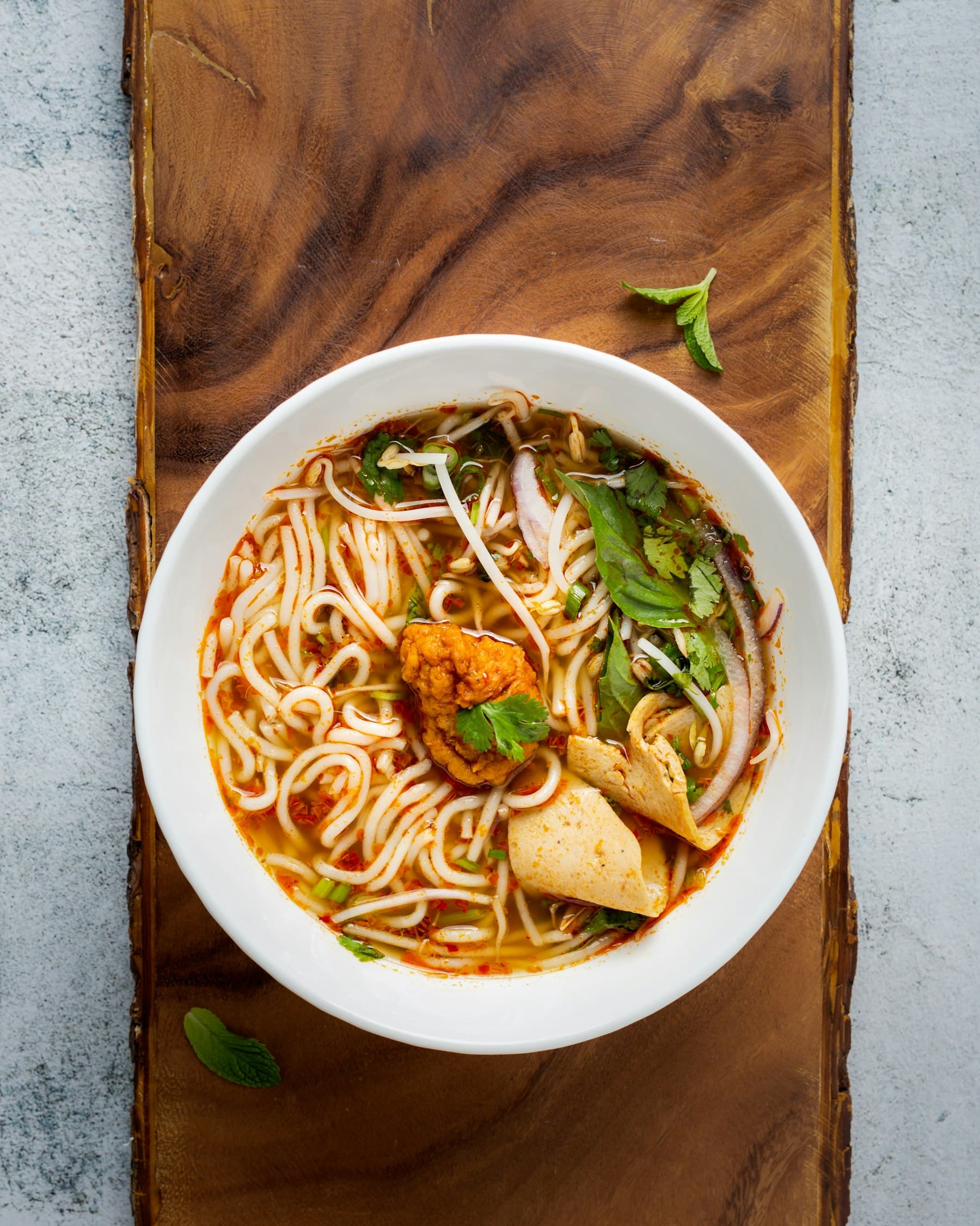 A bowl of hand-pulled noodles in broth with beef and greens