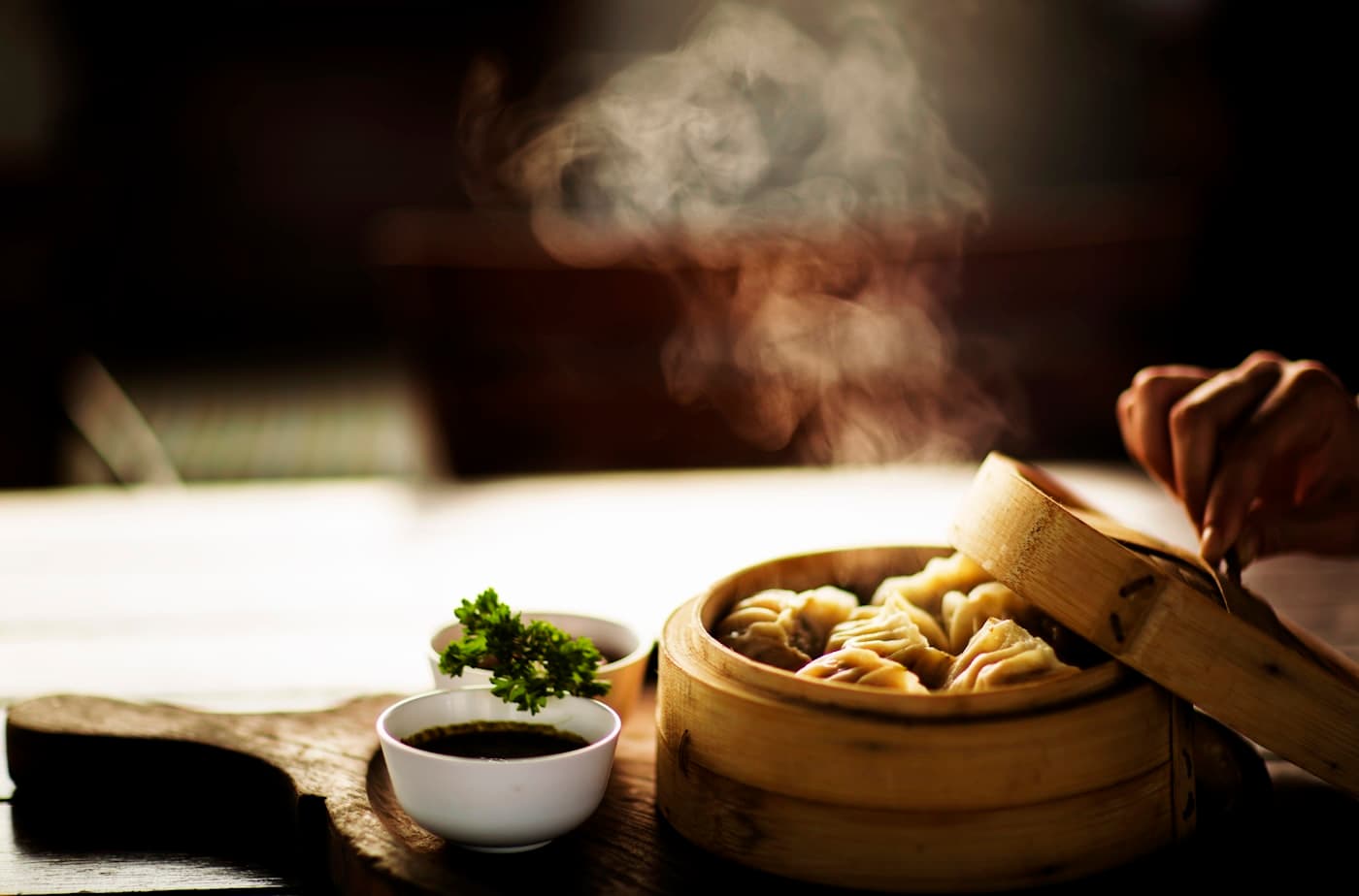 Steamed dumplings in a bamboo basket with steam rising