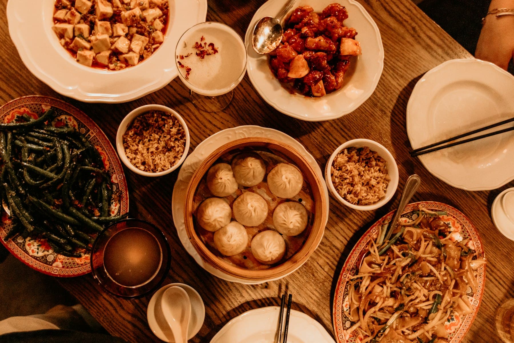A wooden table filled with shared Chinese dishes